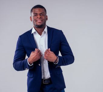 stylish african american in costume black pants and jacket with a big shirt collar posing in studio on white background